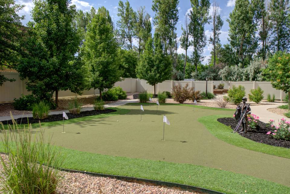 Gardens on Quail outdoor putting green with flags, walking paths, and landscaped trees