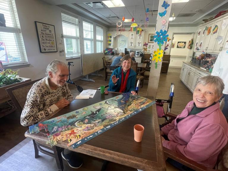 Gardens at Columbine residents working together on a collaborative sea-life art project in the Memory Care activity room.