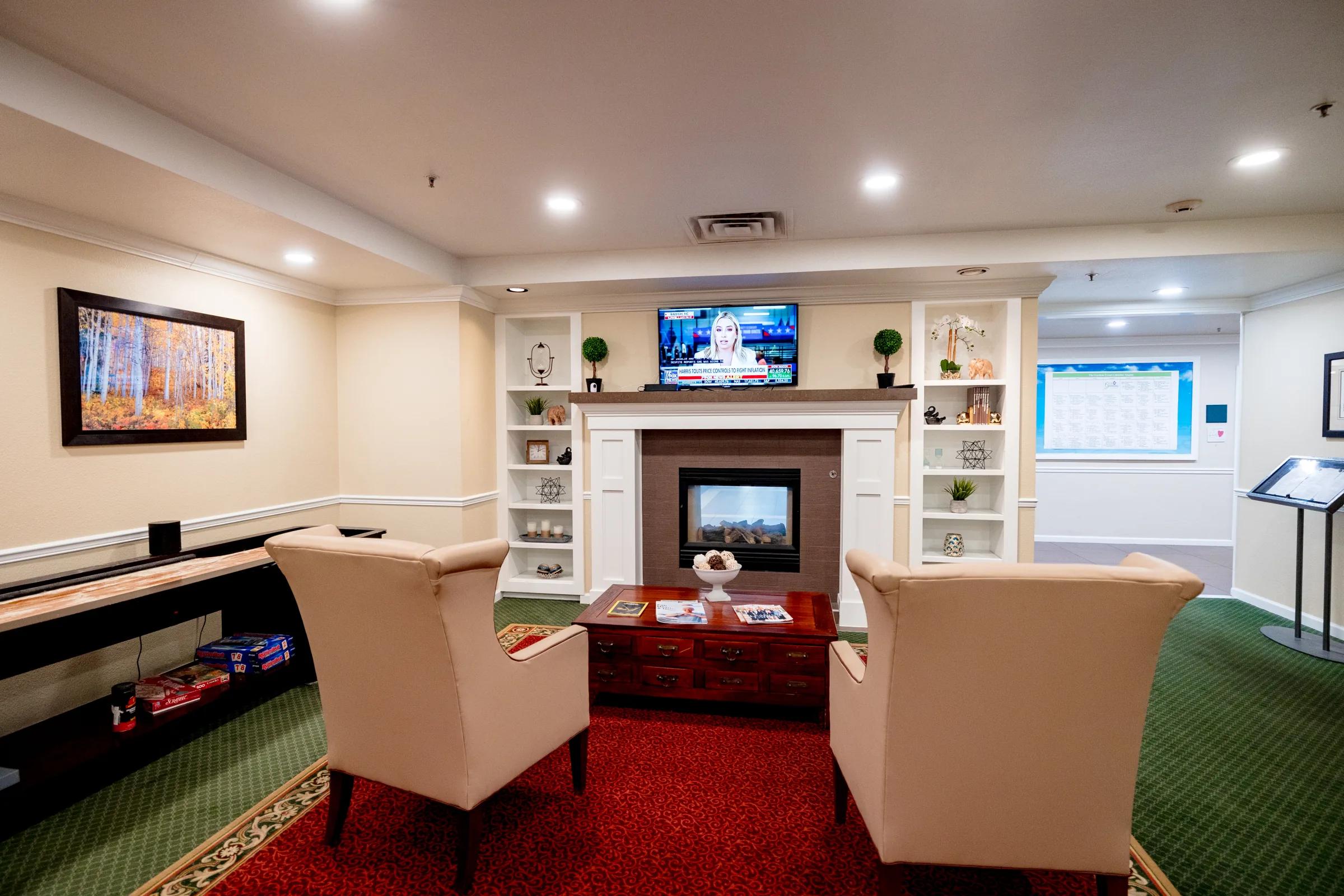 Gardens at Columbine memory care family room with electric fireplace, TV, and wing chairs