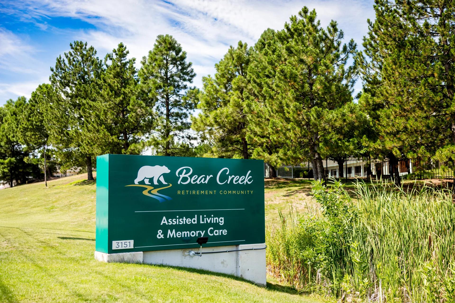 Bear Creek Assisted Living and Memory Care sign beneath tall pine trees