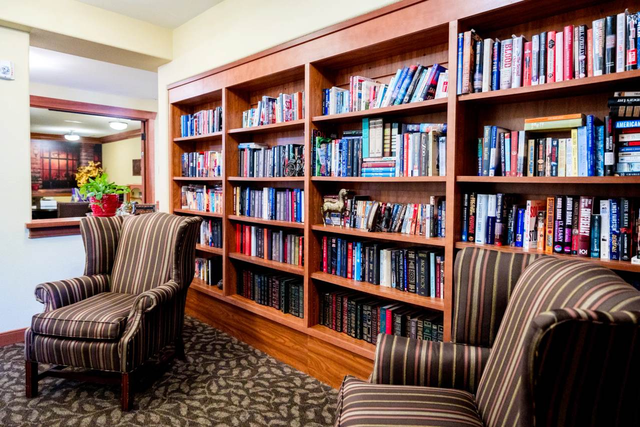 Wide view of the Gardens on Quail library with striped wing chairs and sunflowers