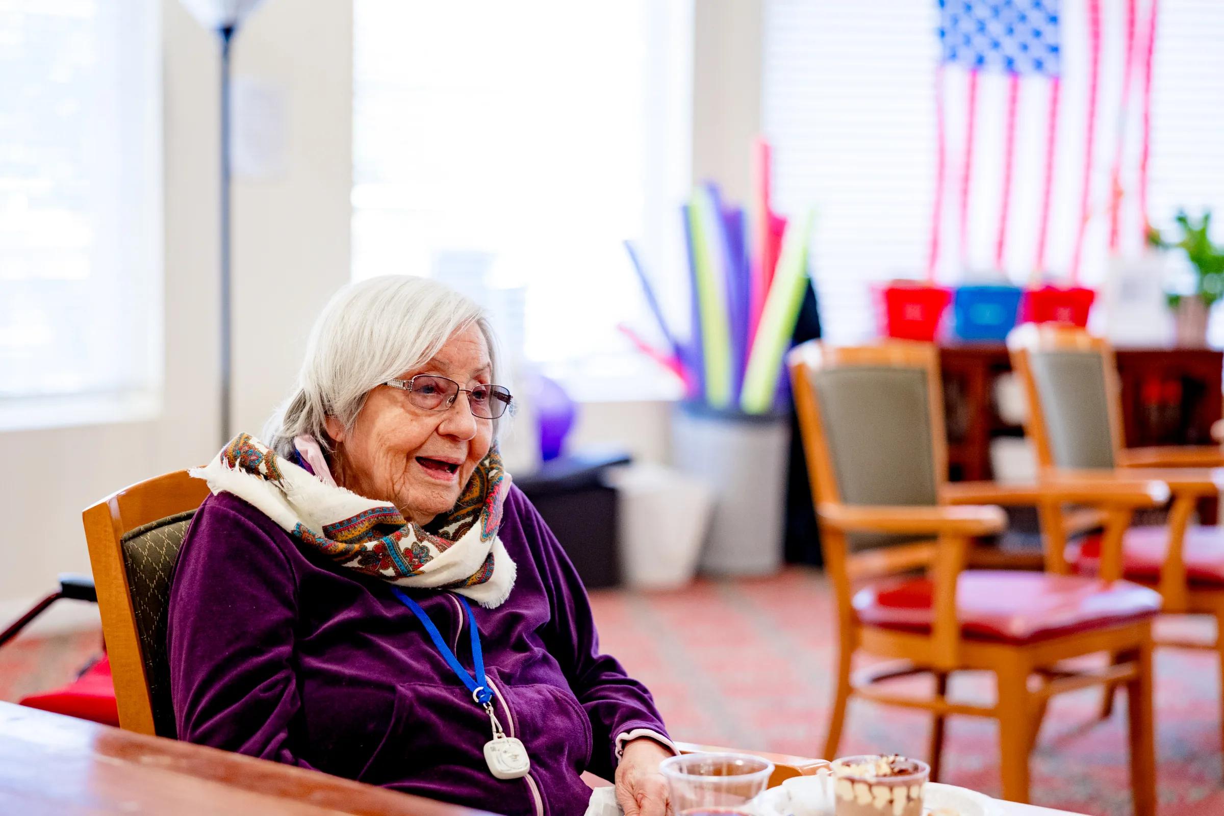 Gardens at Columbine resident laughing at a community event table with American flag in background