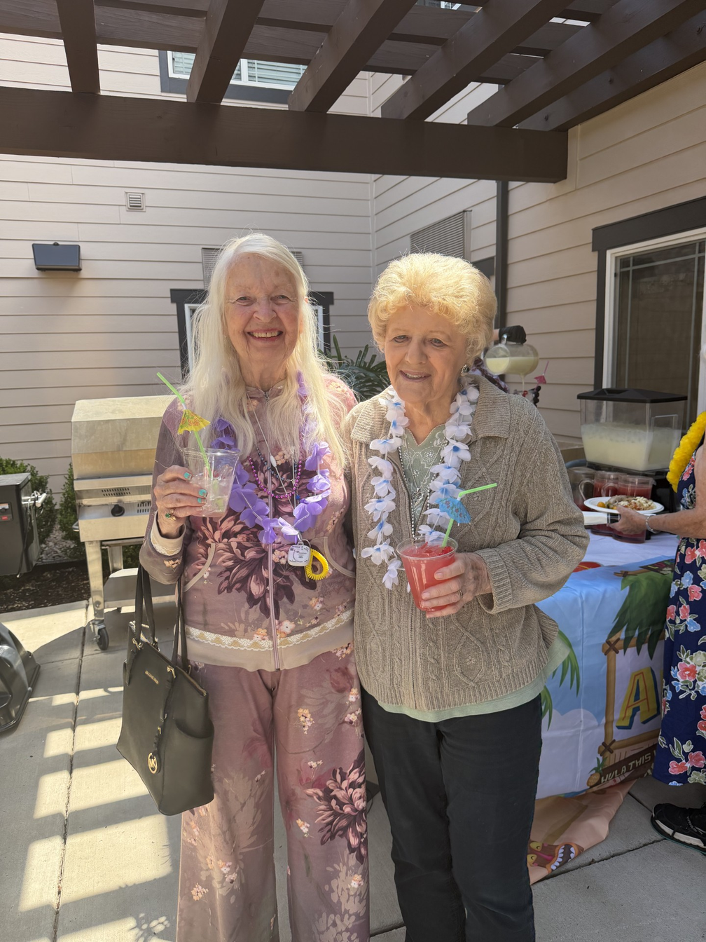 Two Stonebridge residents enjoying a summer celebration with leis and refreshments.