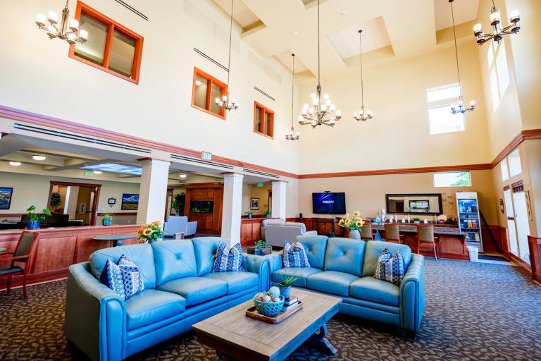Gardens on Quail lobby with blue leather sofas, chandeliers, and open common area