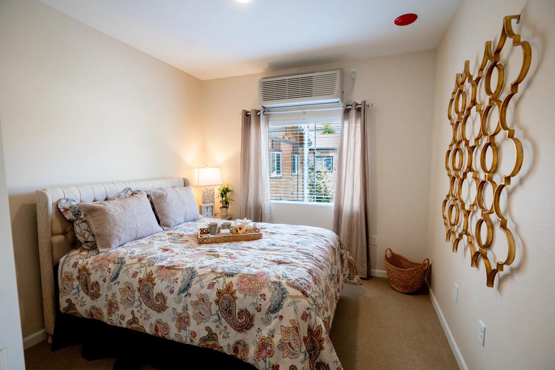 Furnished Stonebridge private suite with patterned bedding and window light