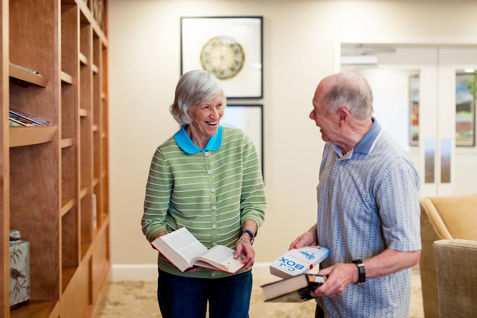 Stonebridge Senior residents laugh together while choosing books in the library