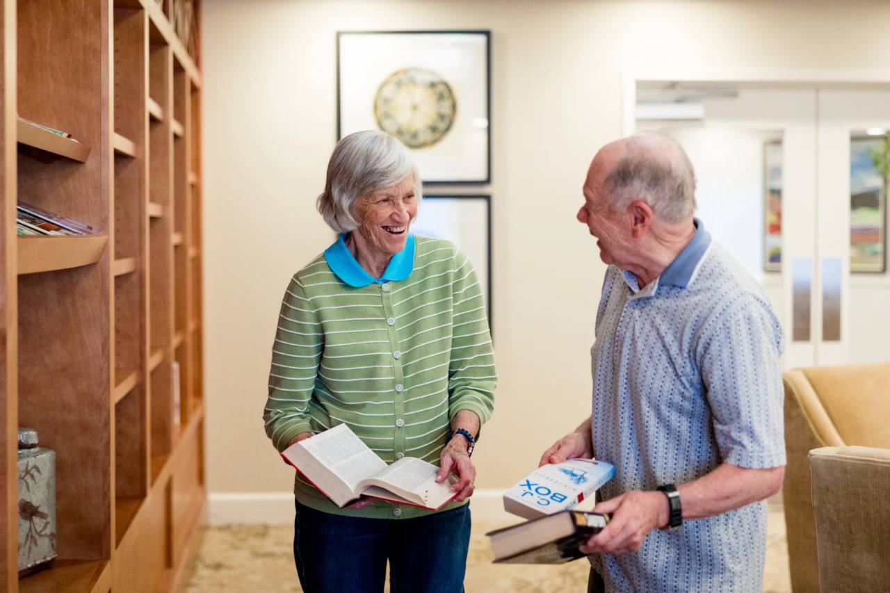 Stonebridge Senior residents laugh together while choosing books in the library