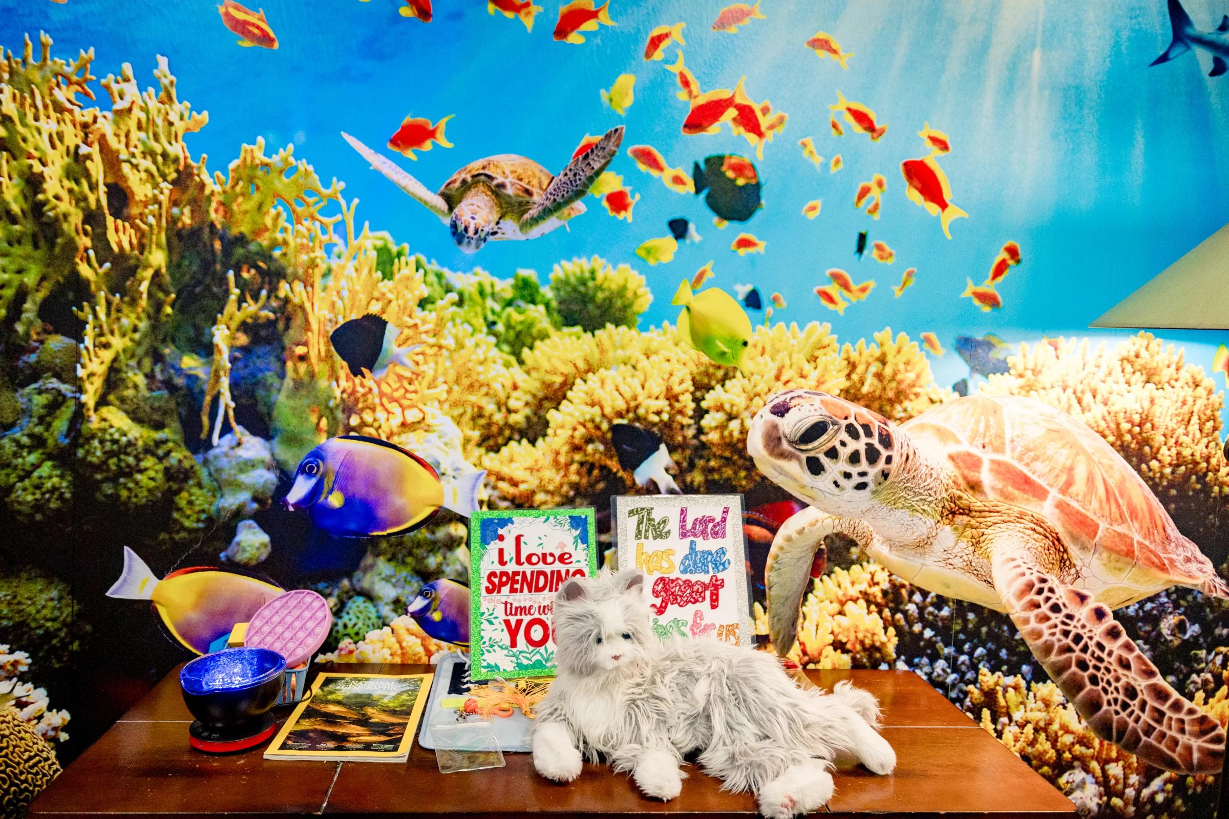 Gardens at Columbine Memory Care wall with a colorful aquarium mural and sea-life display