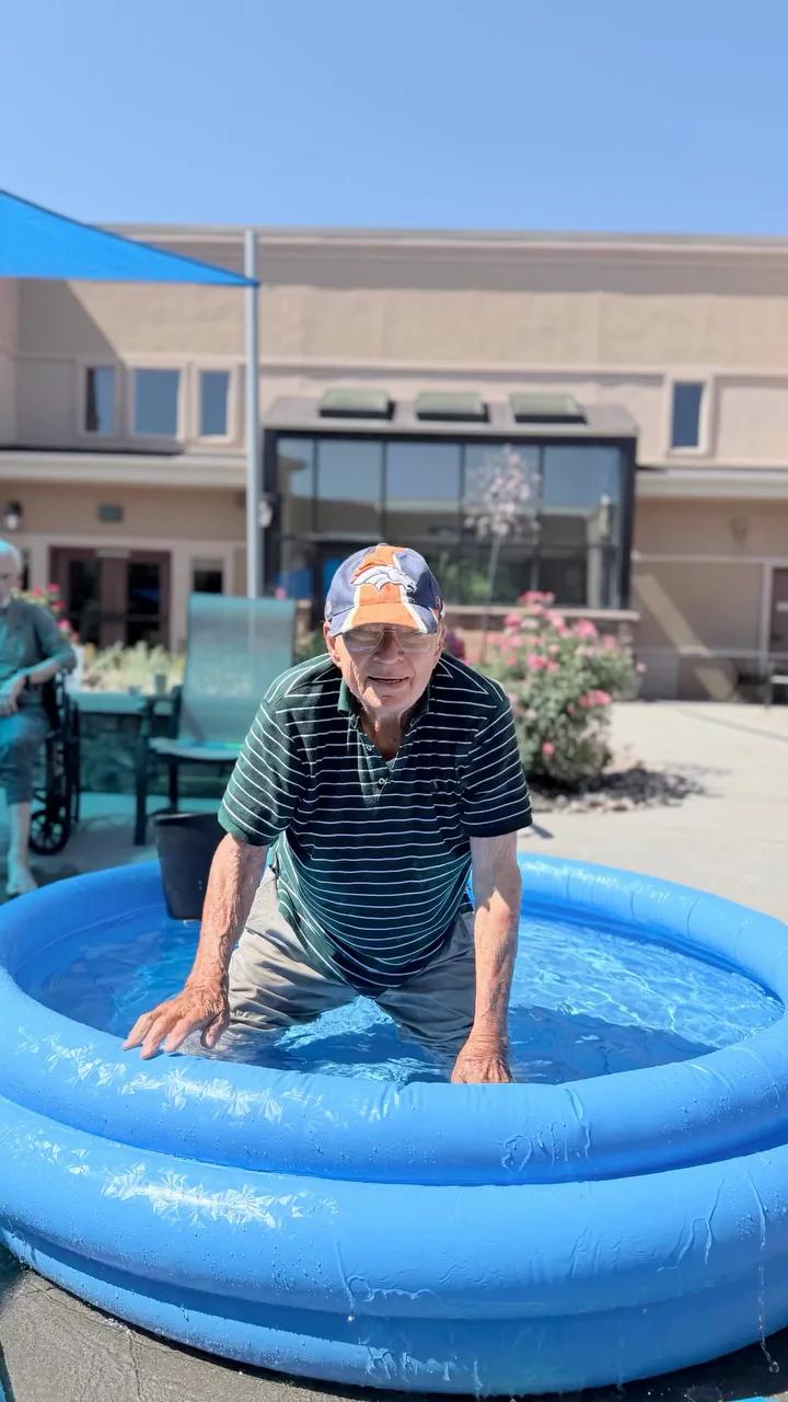 Gardens on Quail resident cooling off in an inflatable pool during a sunny courtyard activity