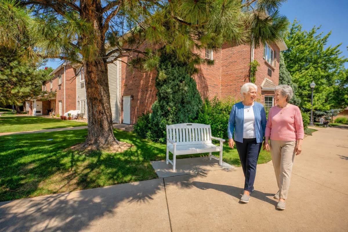 A Bear Creek couple holding hands on an afternoon walk along an evergreen-lined campus path