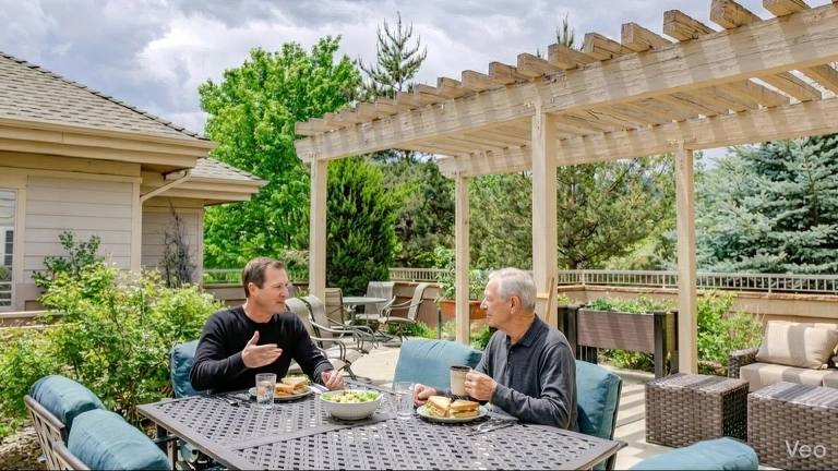 Two people sharing lunch on the Golden Pond patio beneath a pergola