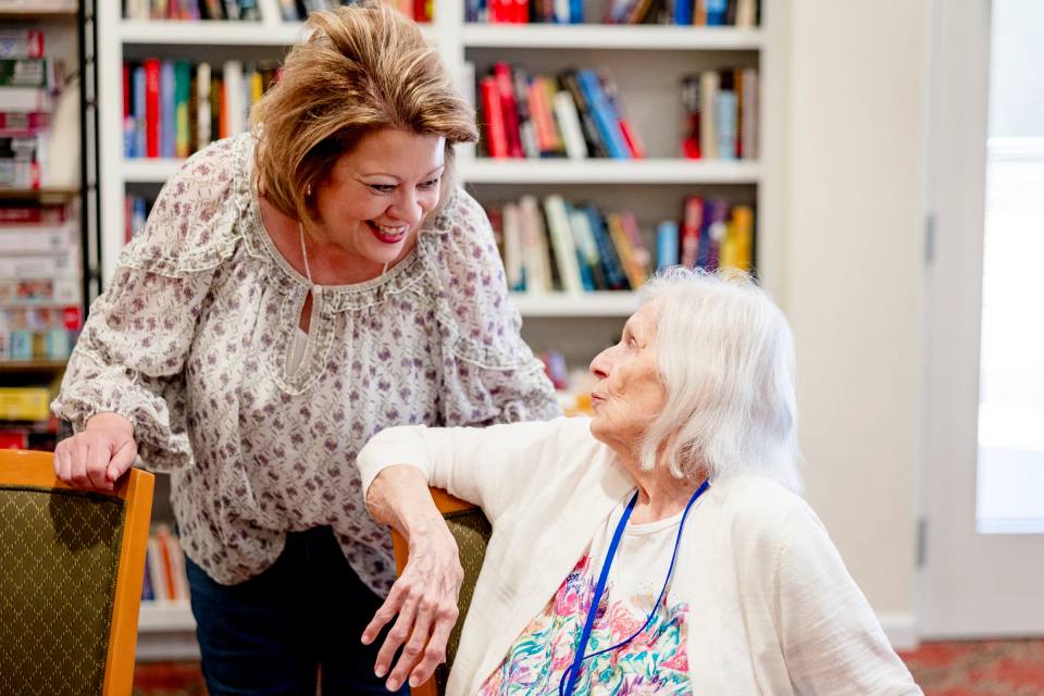 Gardens at Columbine staff member chatting warmly with a resident in the library