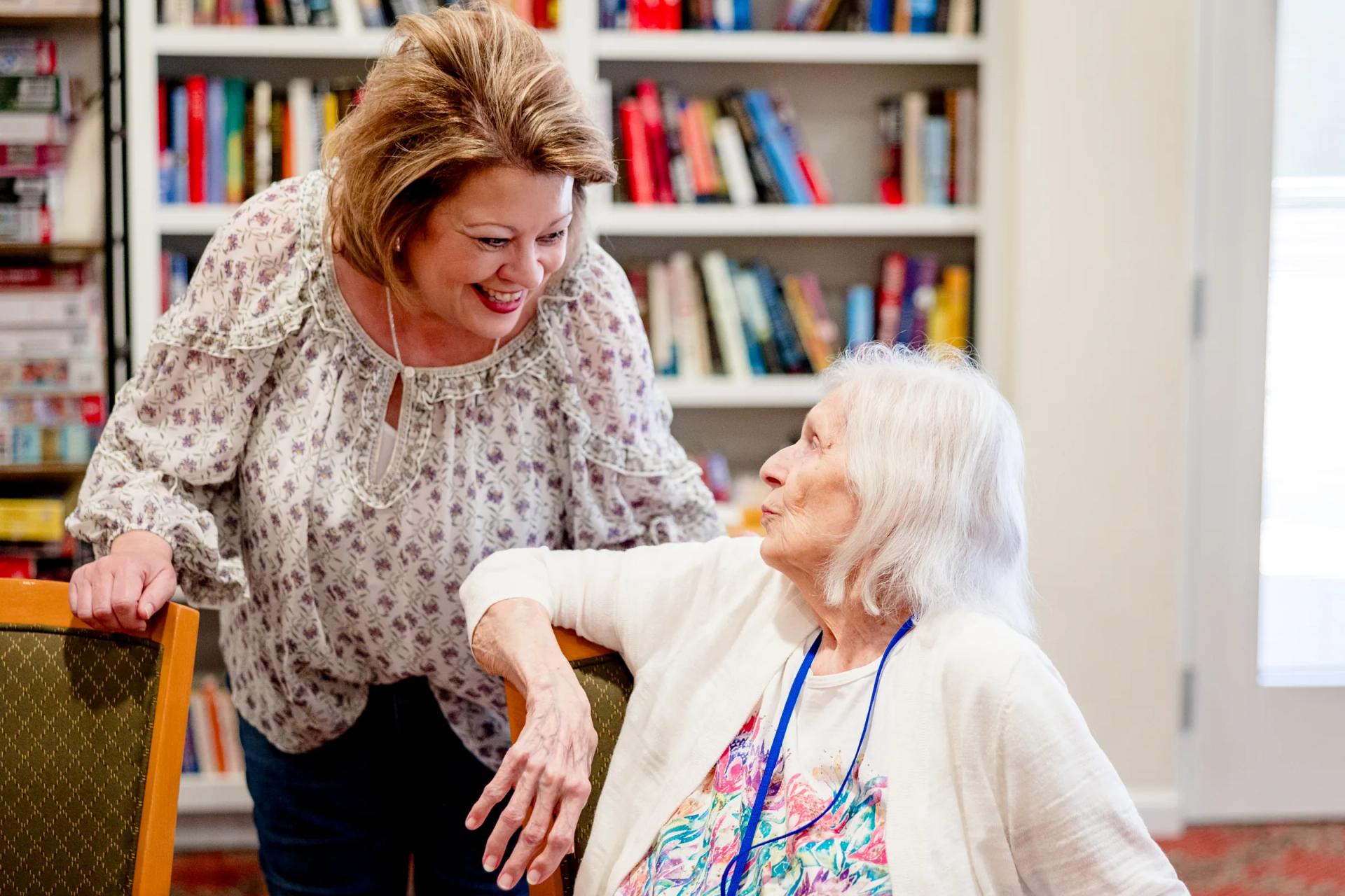 Gardens at Columbine staff member chatting warmly with a resident in the library
