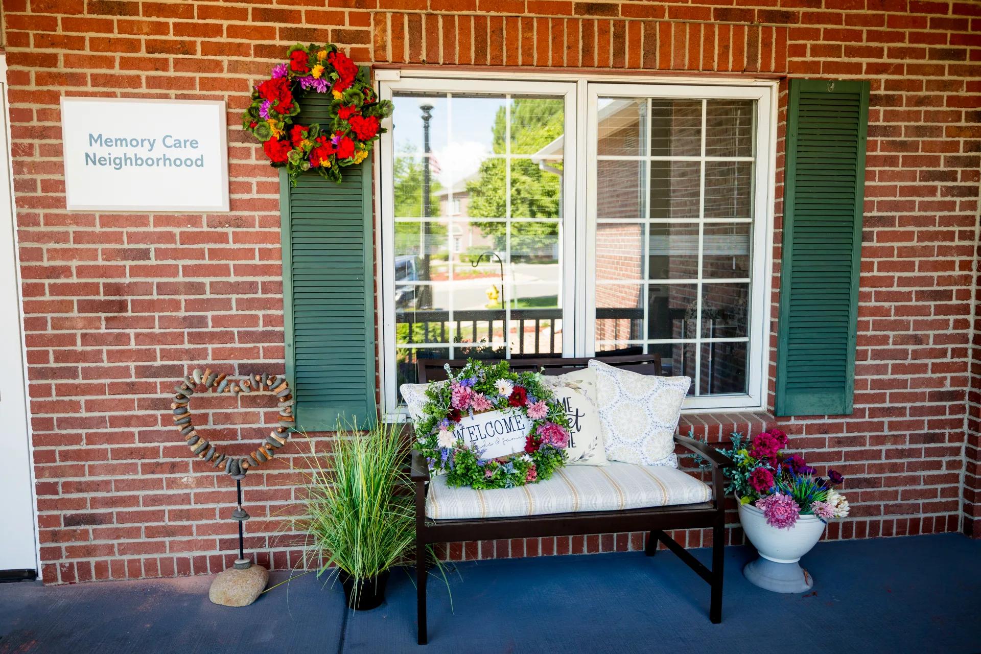 Bench, planters, and a Memory Care Neighborhood sign outside a Bear Creek building
