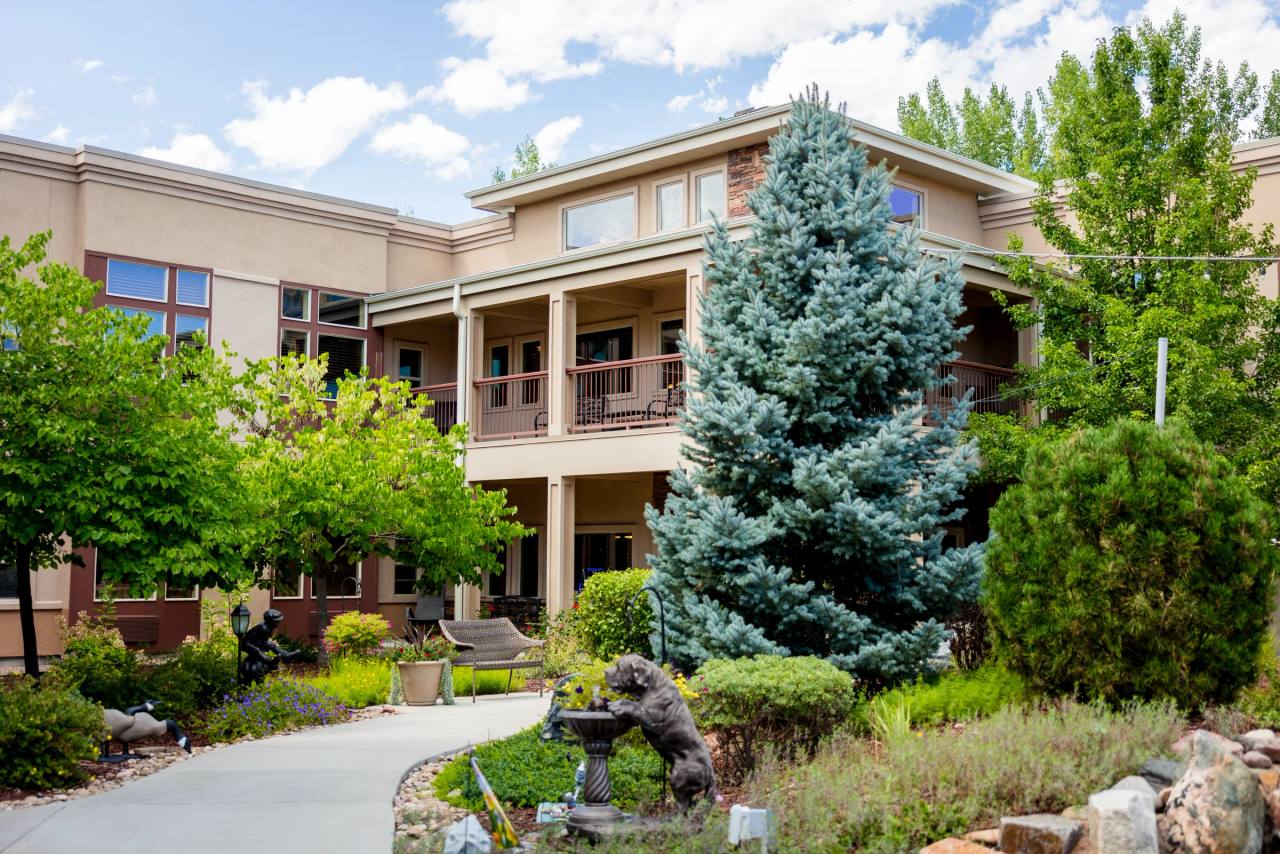 Gardens on Quail exterior with spruce tree and landscaped entrance path
