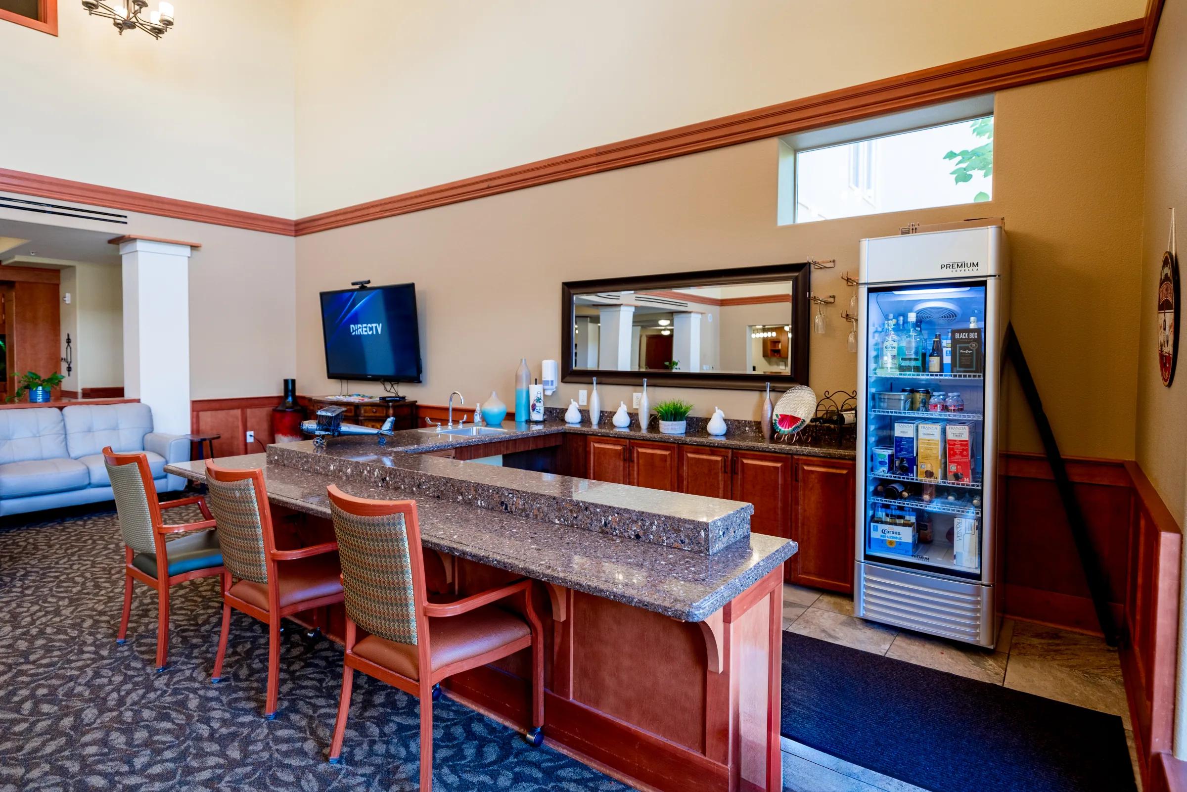 Gardens on Quail bistro bar with granite counter, drink fridge, and TV seating