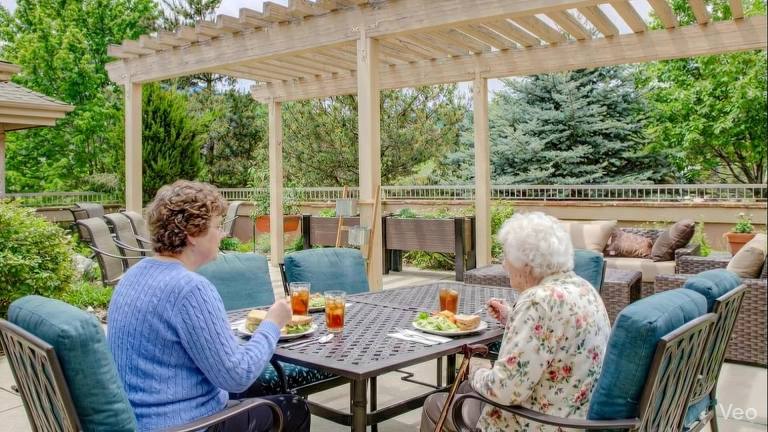 Two people sharing lunch on the Golden Pond patio beneath a pergola