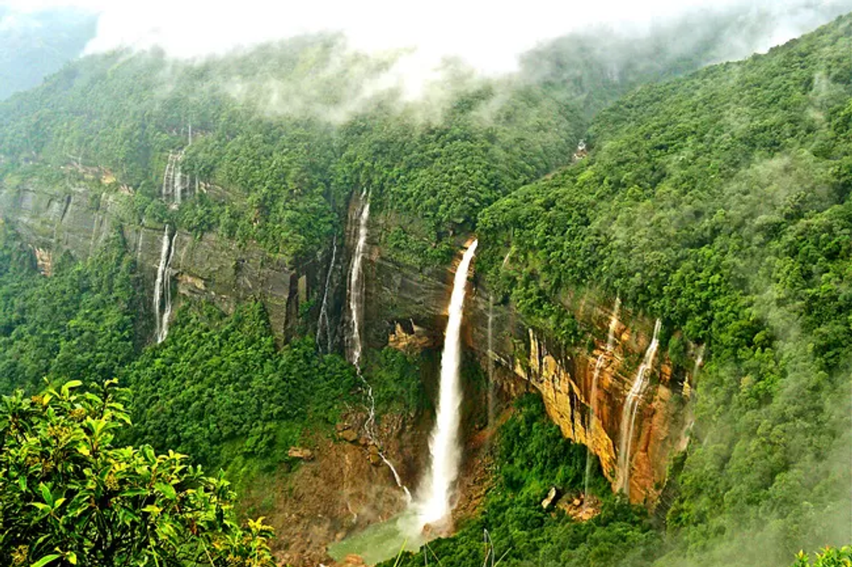 High-volume Nohkalikai Falls in Cherrapunji during the peak monsoon season with mist rising from the base."
