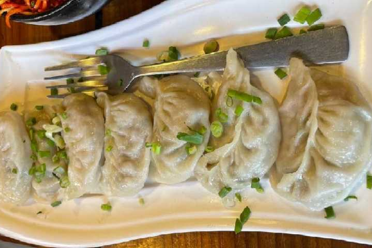 Steaming momos and smoked pork sticks at a local street food stall in Police Bazar.