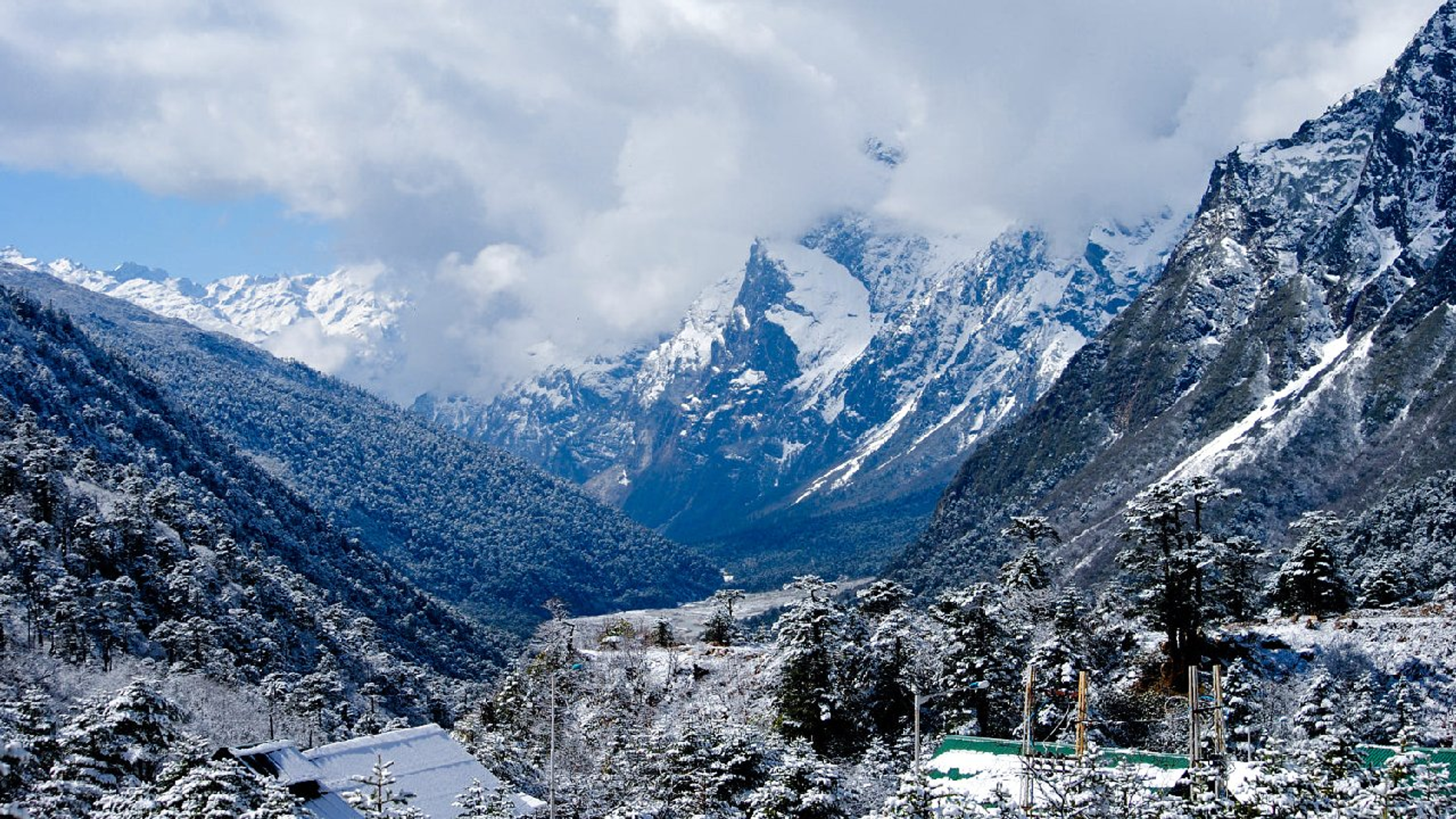 Stunning panoramic view of Lachung village nestled within a lush valley surrounded by snow-capped Himalayan mountains.