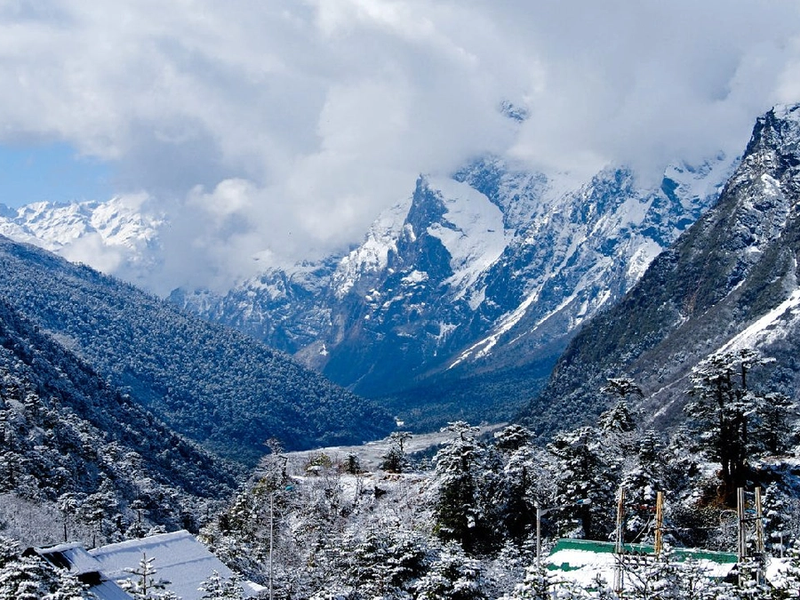Stunning panoramic view of Lachung village nestled within a lush valley surrounded by snow-capped Himalayan mountains.