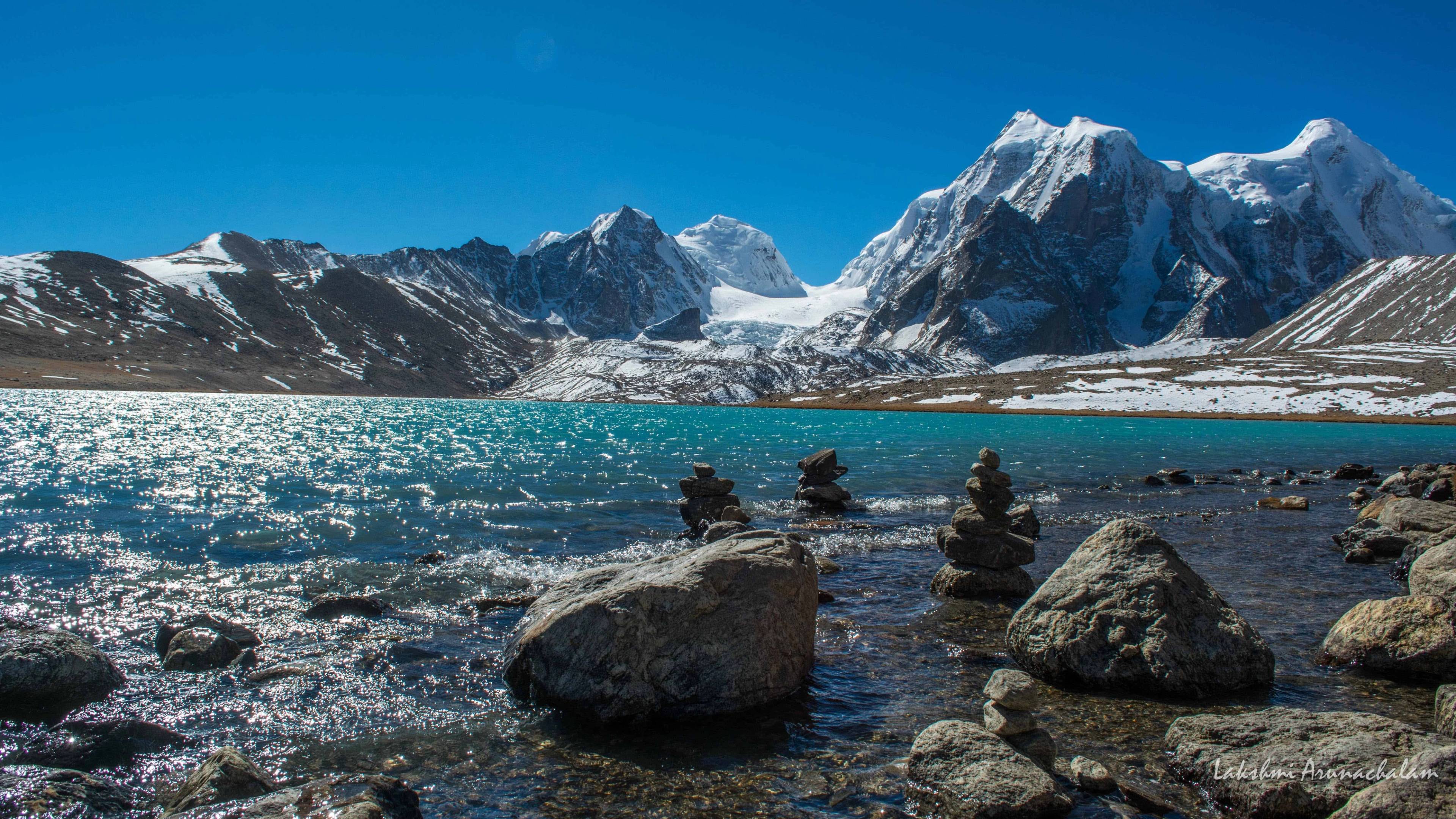 The crystal blue waters of the sacred Gurudongmar Lake reflecting the towering Himalayan peaks.