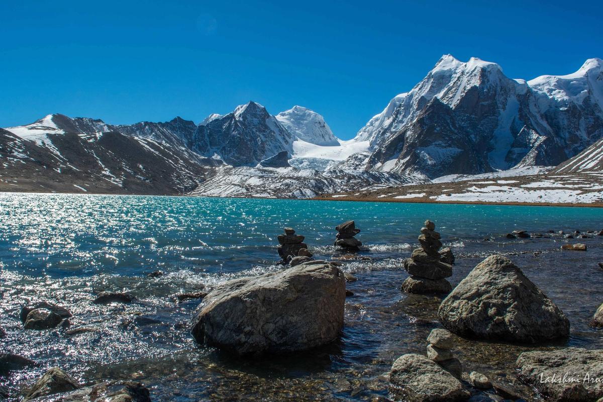 The crystal blue waters of the sacred Gurudongmar Lake reflecting the towering Himalayan peaks.
