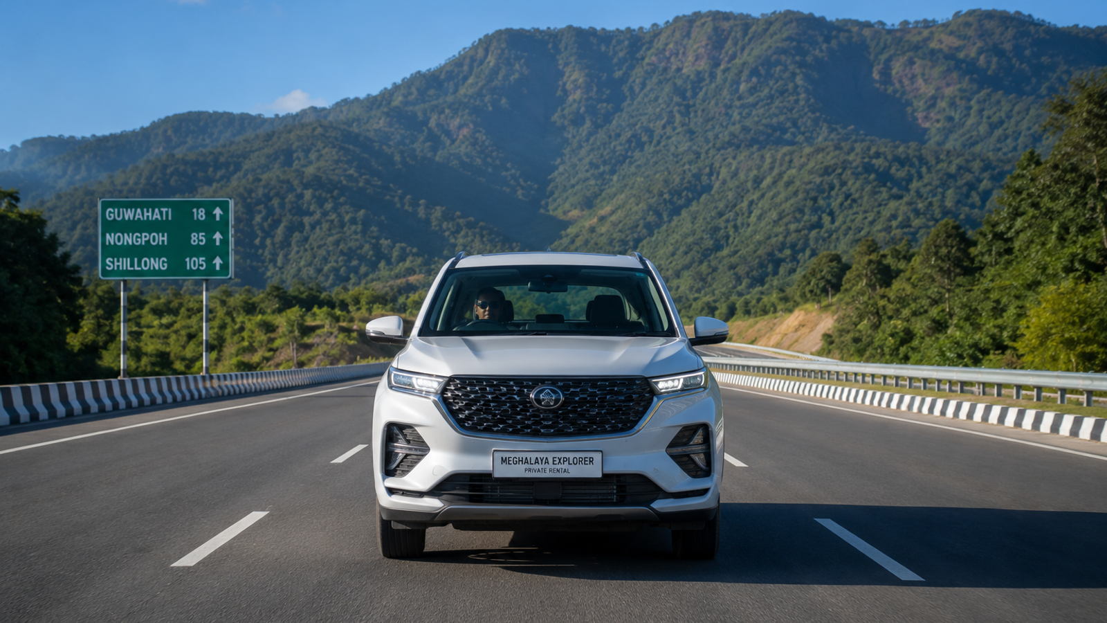 Front view of a private rental SUV driving on the smooth four lane National Highway 6 from Guwahati towards the Meghalaya hills under a clear blue sky