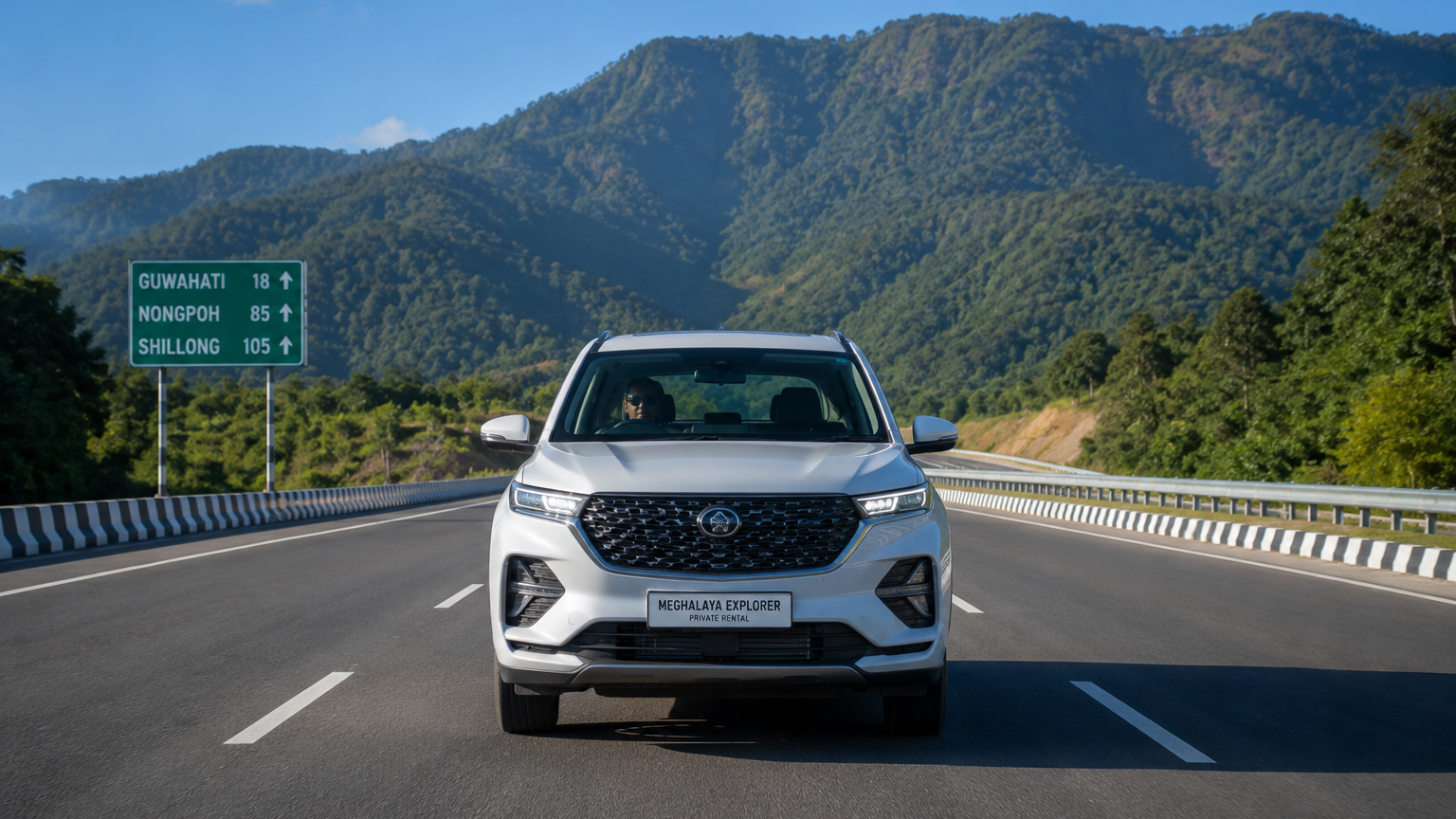 Front view of a private rental SUV driving on the smooth four lane National Highway 6 from Guwahati towards the Meghalaya hills under a clear blue sky