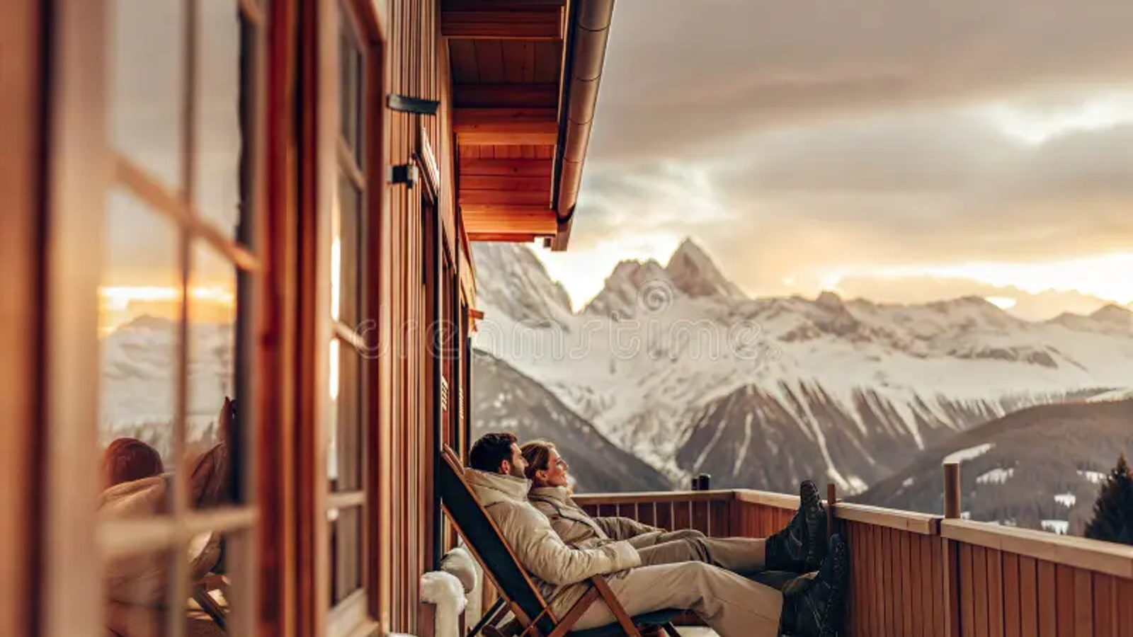 "A romantic couple standing on a wooden balcony overlooking the snow-capped Kanchenjunga mountains during sunrise in Sikkim."