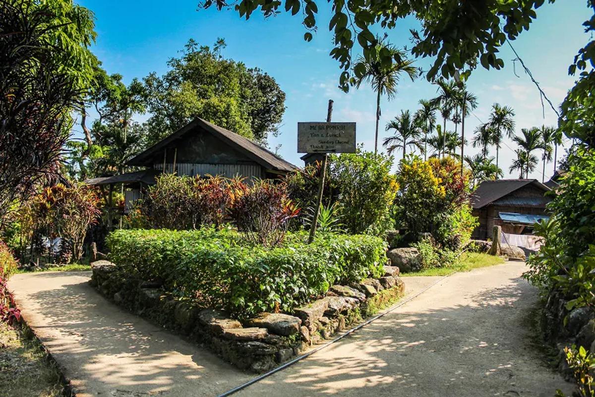 Mawlynnong Asia's Cleanest Village stone path with bamboo dustbins and blooming flower gardens - breeziah sustainable travel guide 2026