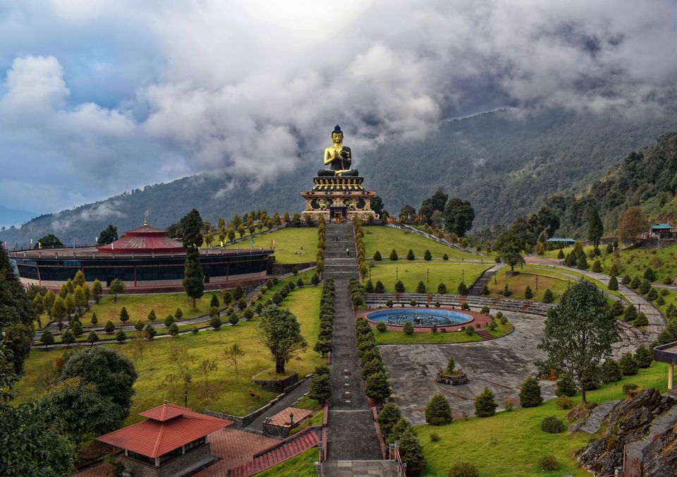 Panoramic view of the 130-foot golden Buddha statue at Tathagata Tsal in Ravangla, Sikkim, framed by snow-capped Himalayan peaks.