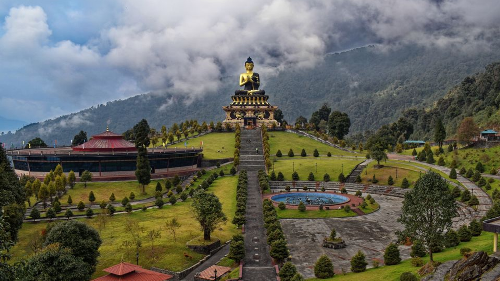 Panoramic view of the 130-foot golden Buddha statue at Tathagata Tsal in Ravangla, Sikkim, framed by snow-capped Himalayan peaks.