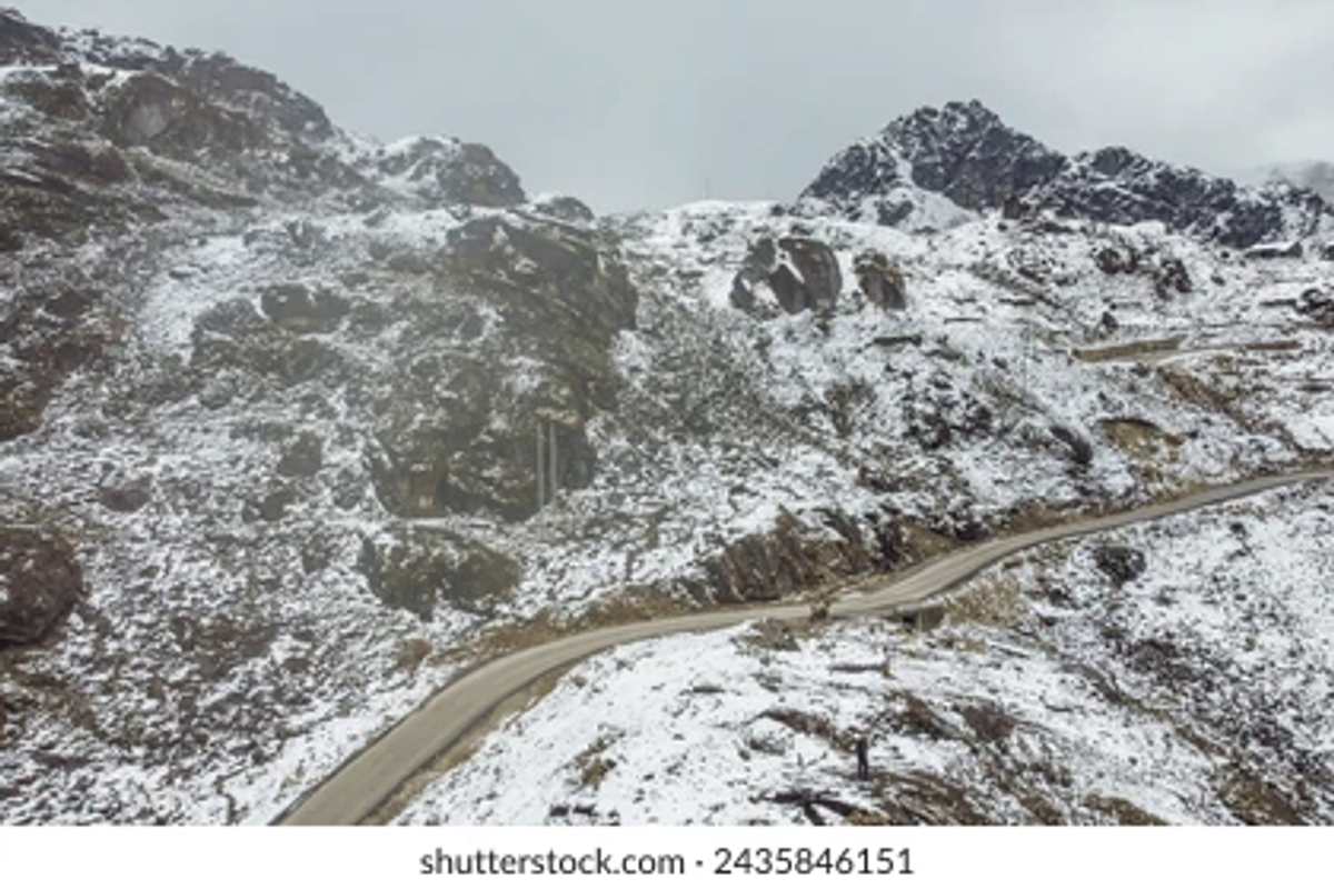 : The winding Trans-Arunachal Highway leading towards Tawang with Himalayan peaks in the background.]