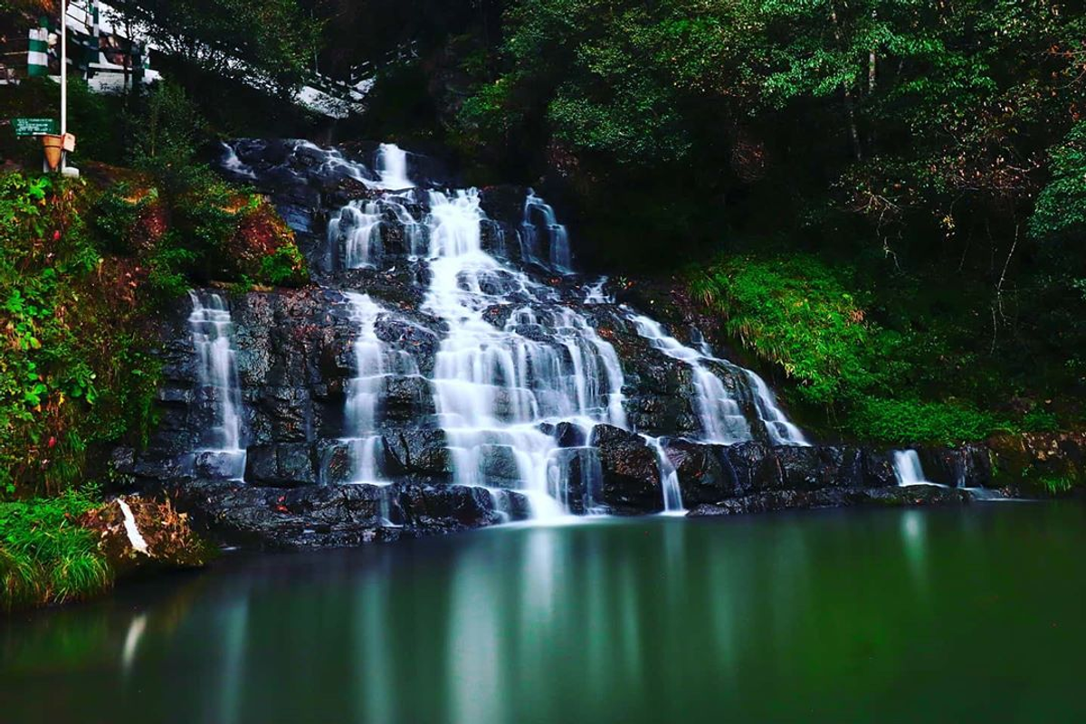 Third tier of Elephant Falls in Shillong, Meghalaya — powerful waterfall cascading into mossy rocks surrounded by dense tropical forest