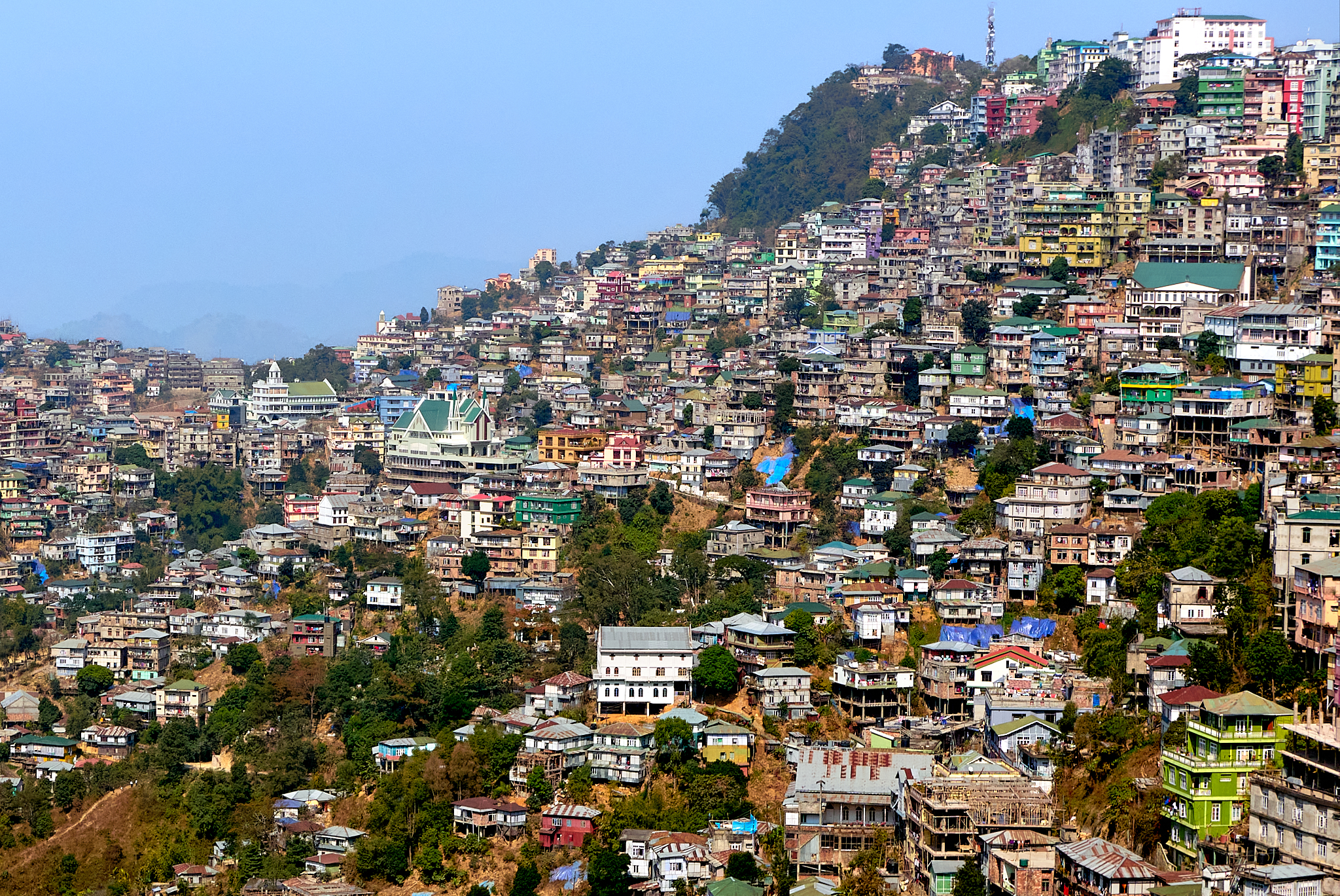Aizawl city buildings stacked along green mountain ridges under a clear sky