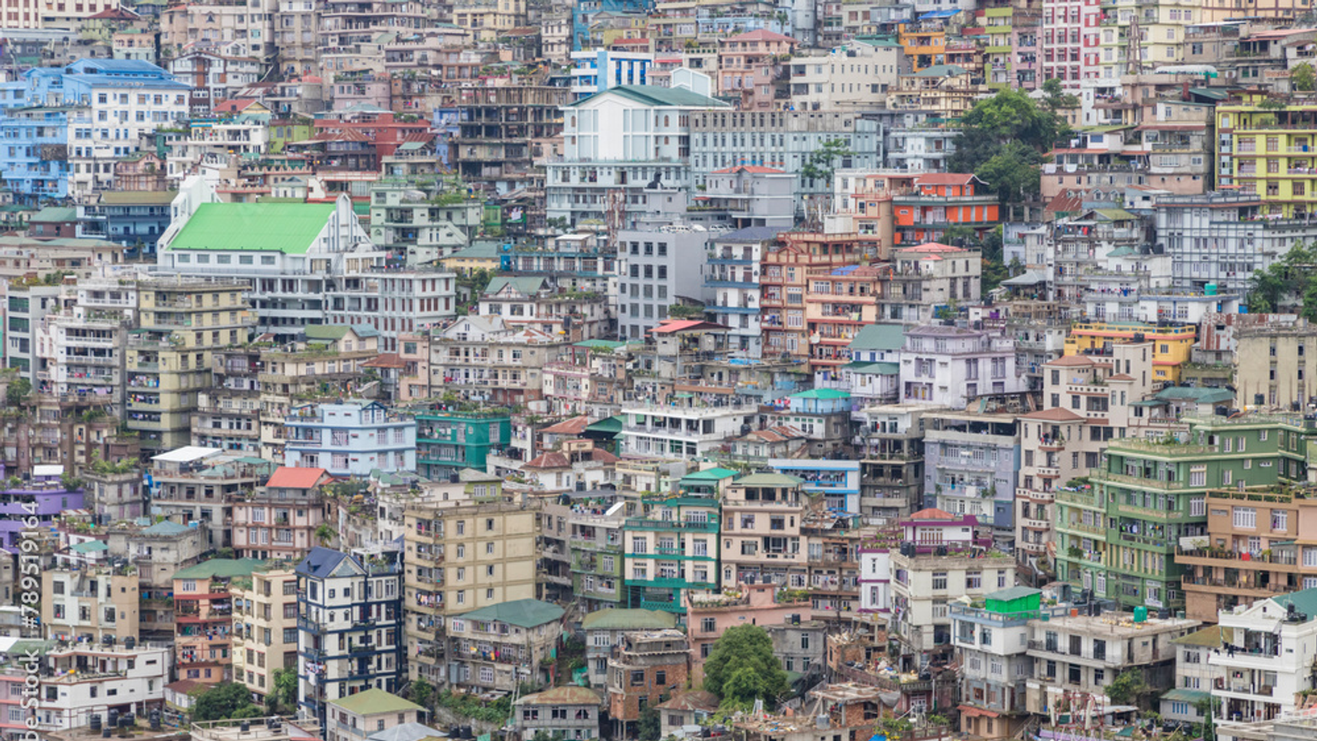 Aizawl city in Mizoram with colorful buildings on steep hillsides and churches perched on ridge peaks in Northeast India.
