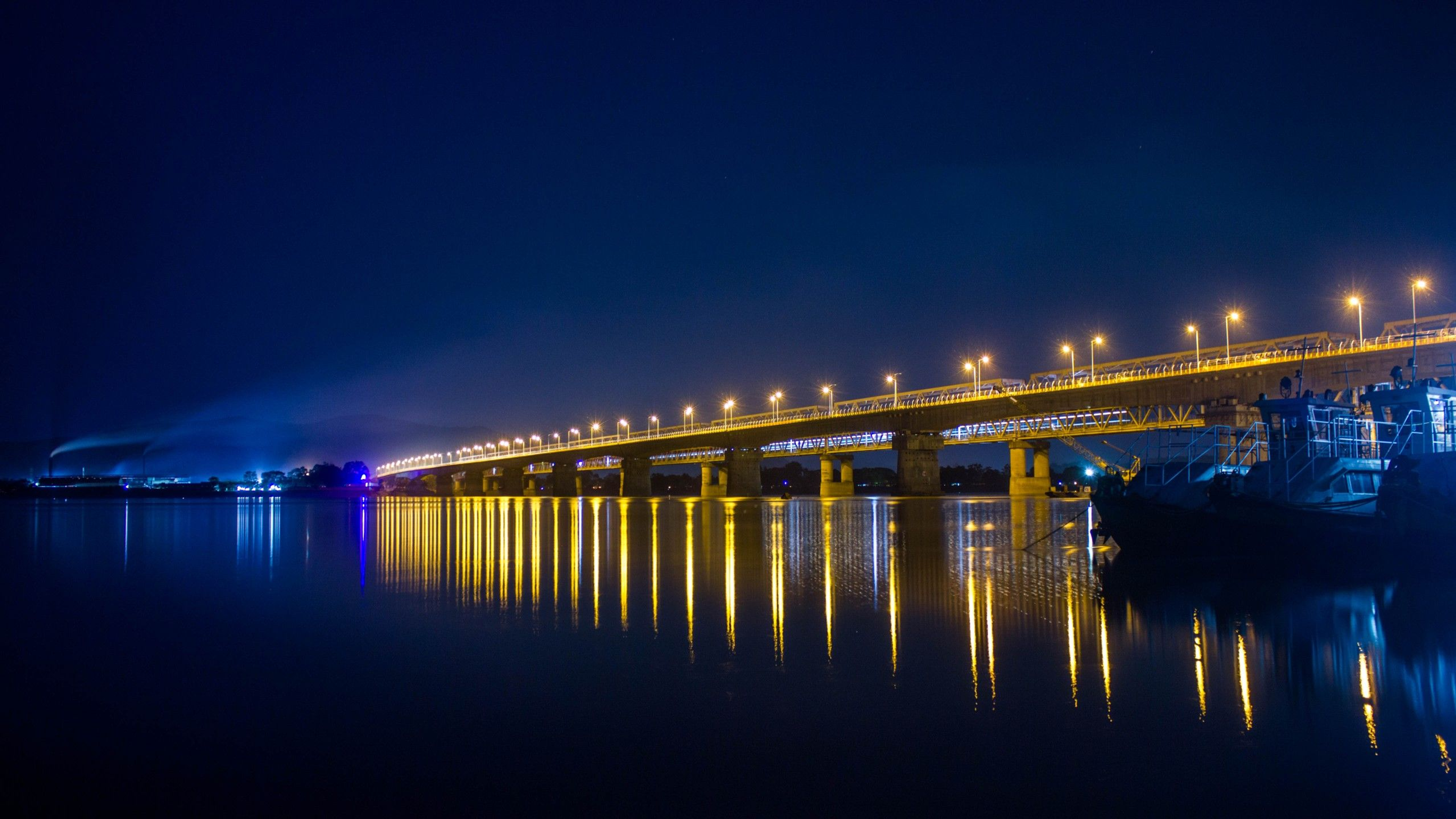 Saraighat Bridge over Brahmaputra River at night with city lights reflected in water Guwahati