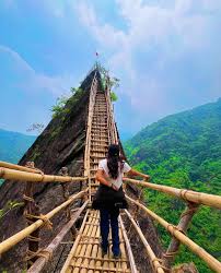A hiker crossing a traditional khasi bamboo skywalk on the mawryngkhang trek in meghlaya