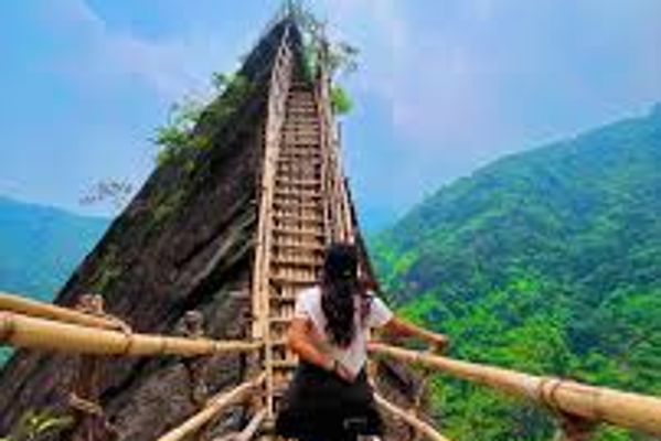 A hiker crossing a traditional khasi bamboo skywalk on the mawryngkhang trek in meghlaya
