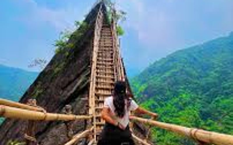 A hiker crossing a traditional khasi bamboo skywalk on the mawryngkhang trek in meghlaya