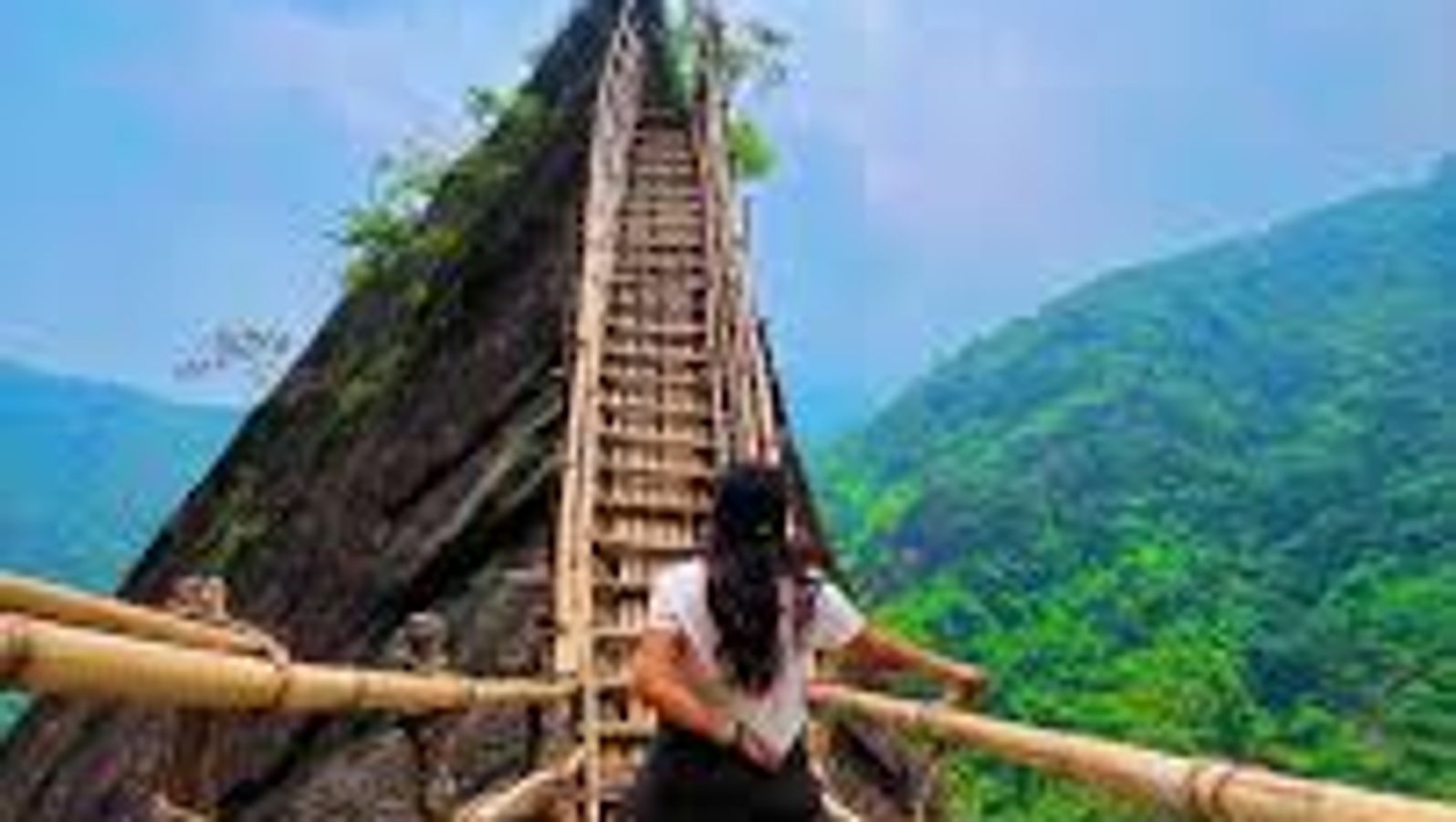 A hiker crossing a traditional khasi bamboo skywalk on the mawryngkhang trek in meghlaya