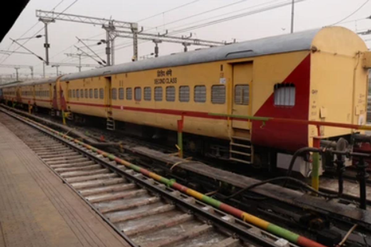 A view of a yellow and red express train standing at the platform of Guwahati railway station.