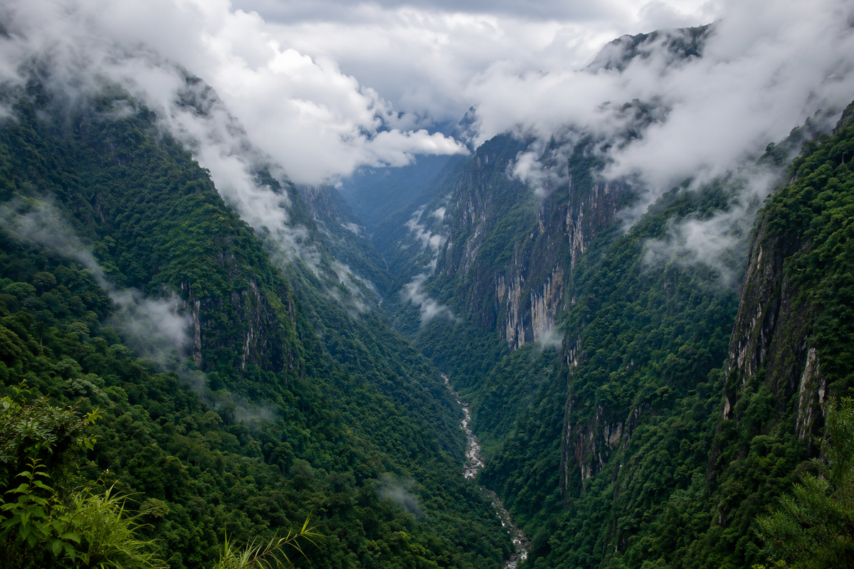 Deep green V-shaped mountain gorge canyon at Mawkdok Valley in Meghalaya with low hanging white clouds and rolling mist