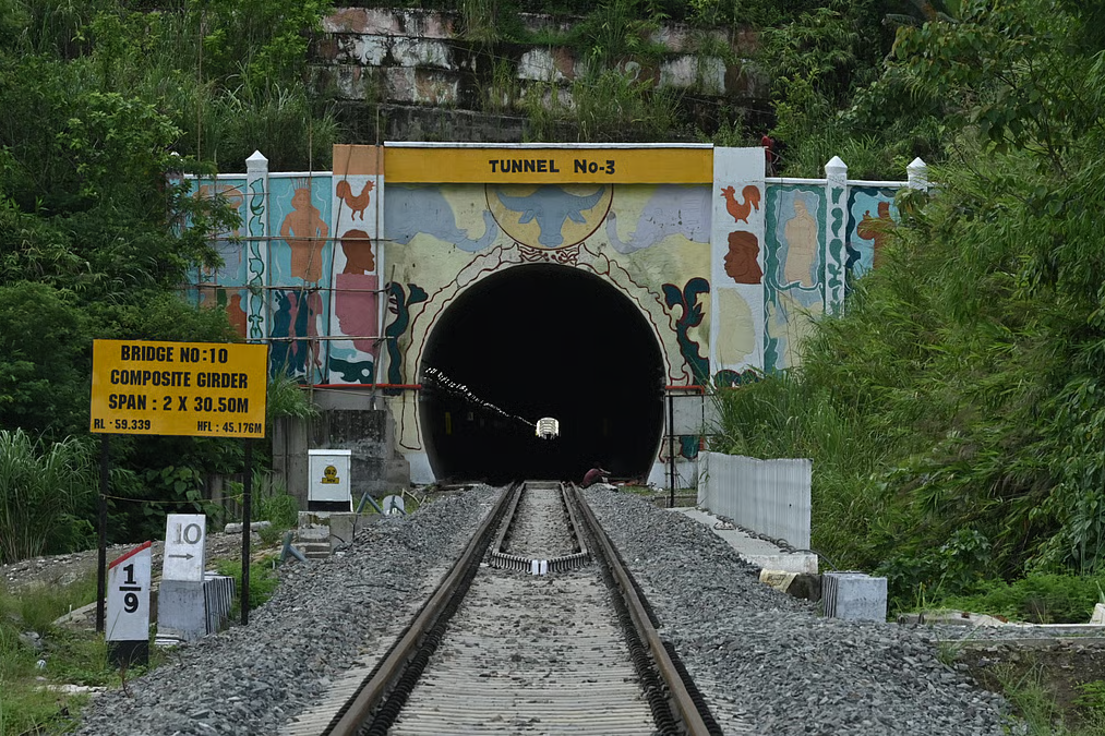 Passenger train coming out of a tunnel on the Bairabi Sairang railway line in the green Mizo hills