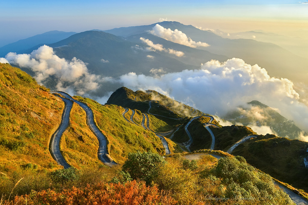Aerial panoramic view of the winding Zuluk zig-zag roads on the Old Silk Route in East Sikkim during a golden sunrise."
