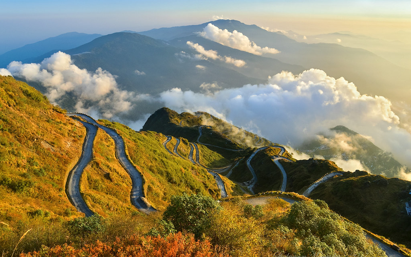 Aerial panoramic view of the winding Zuluk zig-zag roads on the Old Silk Route in East Sikkim during a golden sunrise."