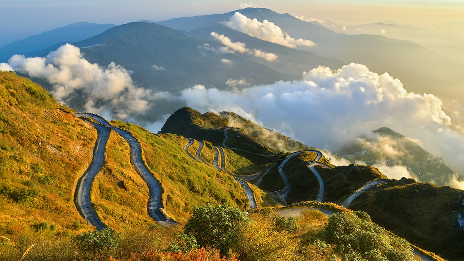 Aerial panoramic view of the winding Zuluk zig-zag roads on the Old Silk Route in East Sikkim during a golden sunrise."
