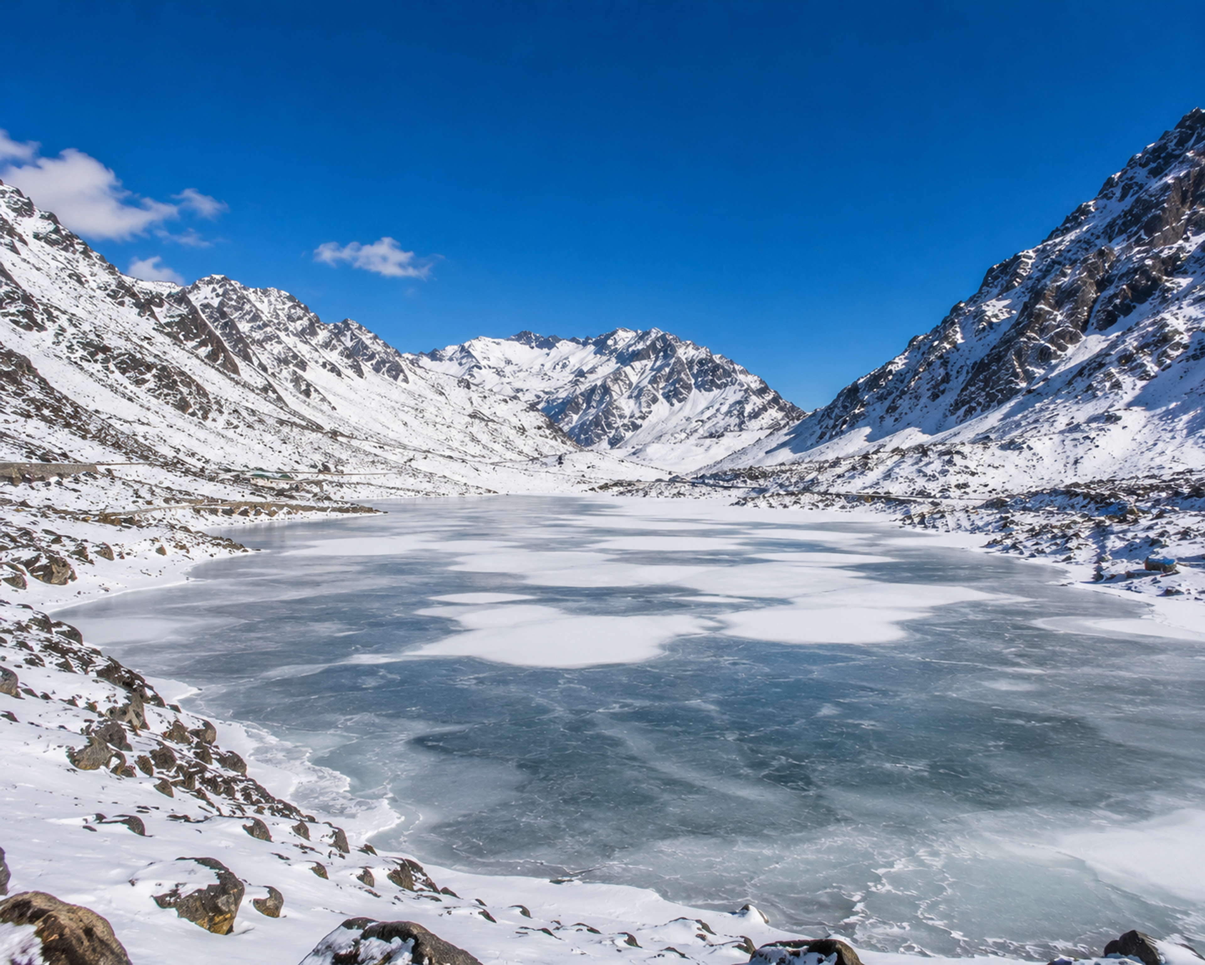 Sweeping winter landscape of frozen Sela Lake in Arunachal Pradesh surrounded by snow-covered mountain walls.