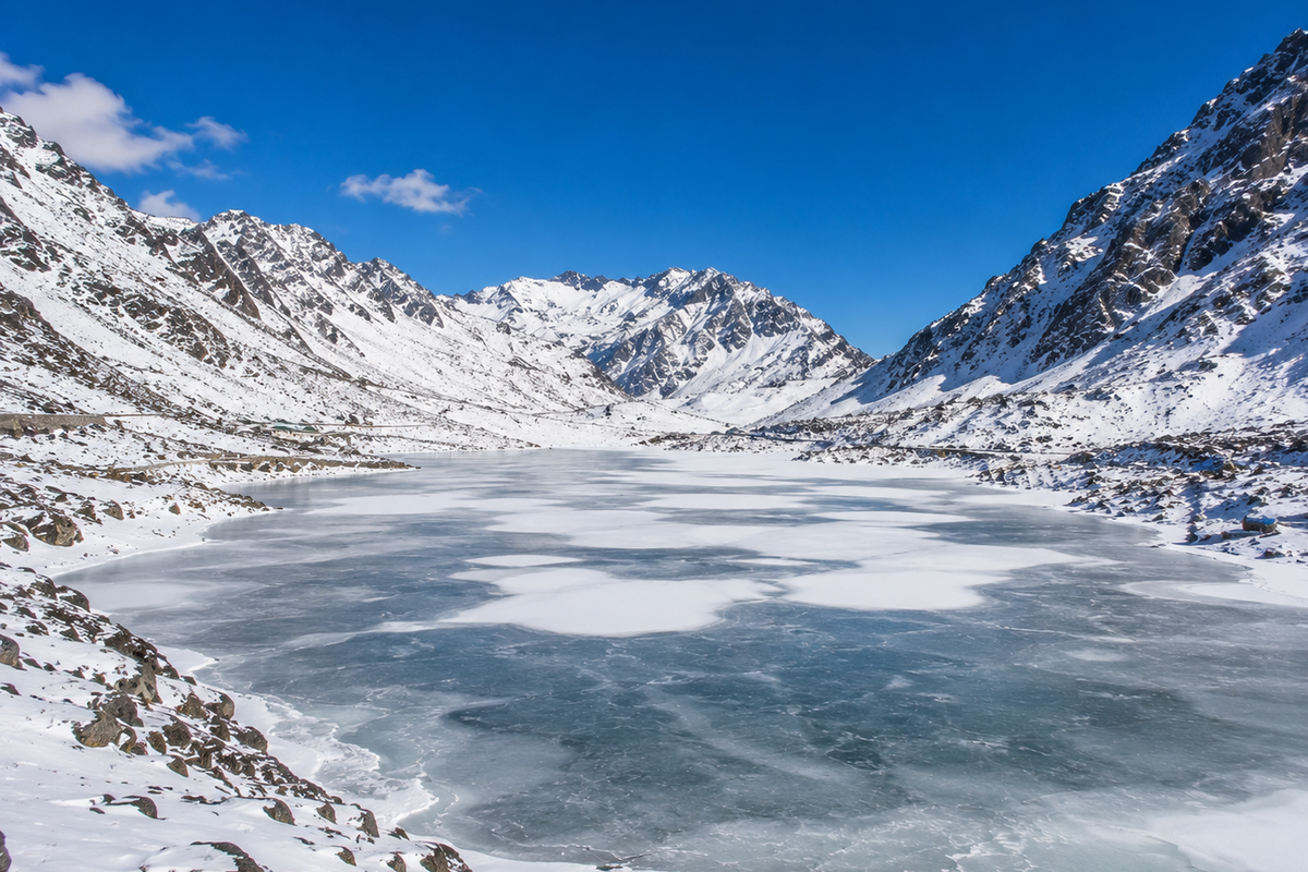 Sweeping winter landscape of frozen Sela Lake in Arunachal Pradesh surrounded by snow-covered mountain walls.